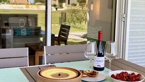 A table with a bottle of wine, glasses, a bowl of cherries, and a wooden bowl with a lid. - Charming Apartment with Private Garden & Pool (Vilamoura)