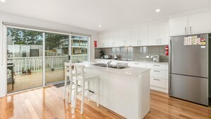 Una cocina moderna con una isla grande, armarios blancos y un refrigerador de acero inoxidable.