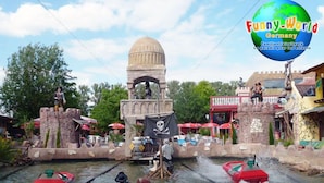 A water ride with a pirate theme, including a ship, a pirate flag, and a castle-like structure.