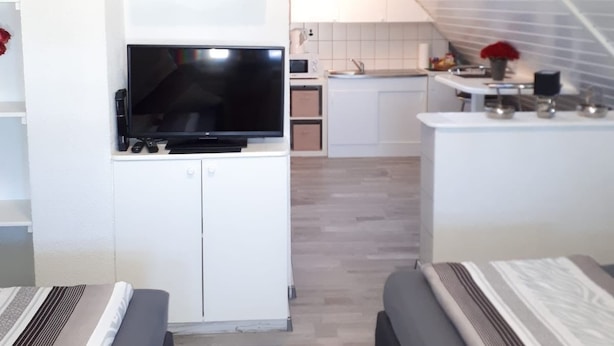 A compact, modern apartment with a kitchenette, a dining area, and a living room.
