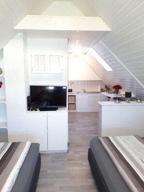 Un apartamento moderno y compacto con kitchenette, comedor y sala de estar.