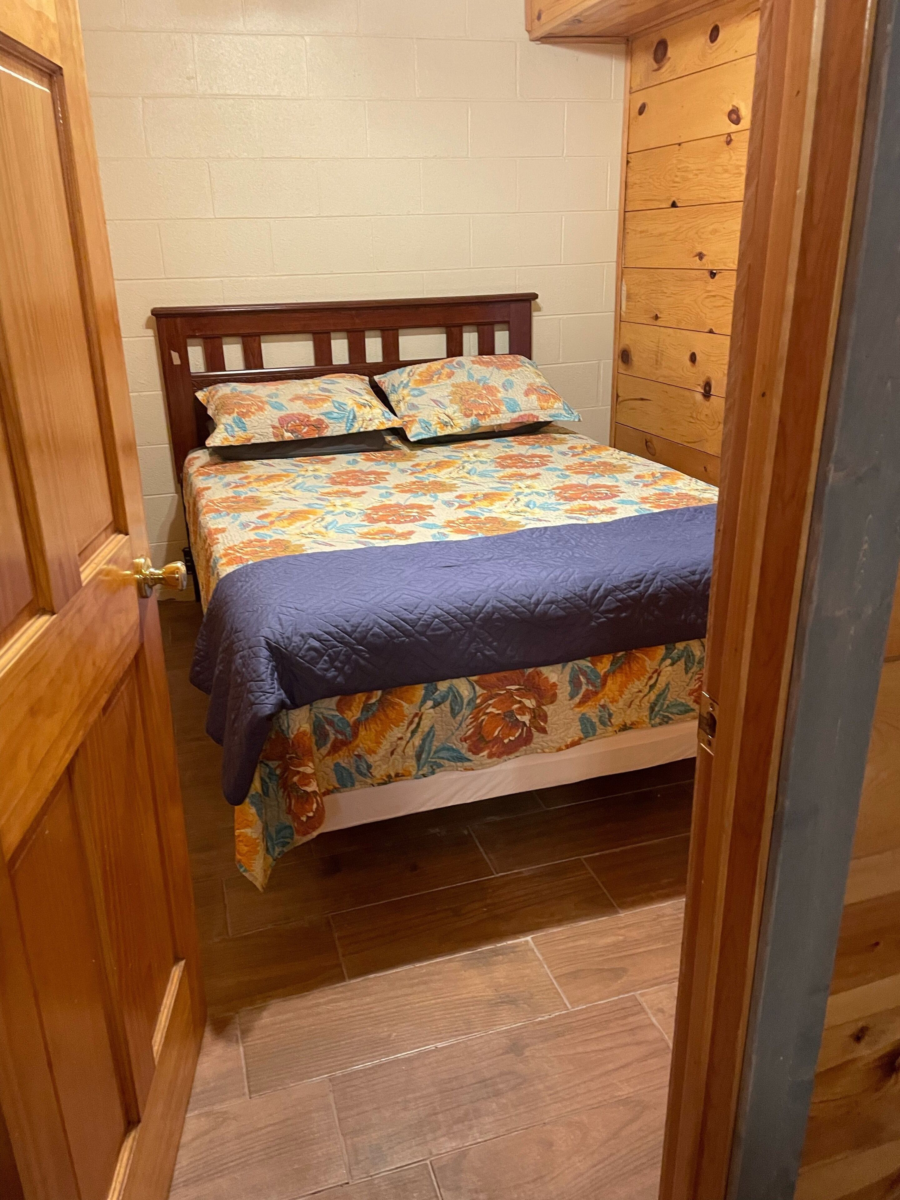 A bedroom with a wooden bed, floral bedding, and a wooden wardrobe.