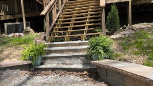 A wooden staircase leading up to a deck, surrounded by gravel and potted plants.