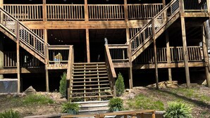 A rustic wooden building with a central staircase, surrounded by gravel and potted plants.