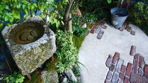 Un jardín con una pila de piedra, un sendero de ladrillo y diversas plantas.