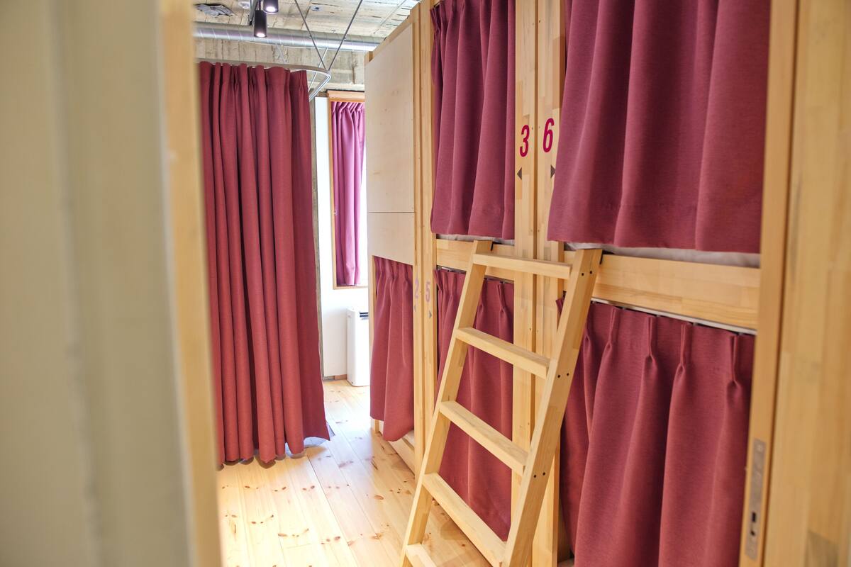 Un pasillo con paredes de madera y cortinas rojas, una escalera de madera y el número 36 a la vista.