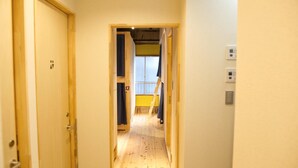Un pasillo estrecho con suelo de madera y puertas a ambos lados.