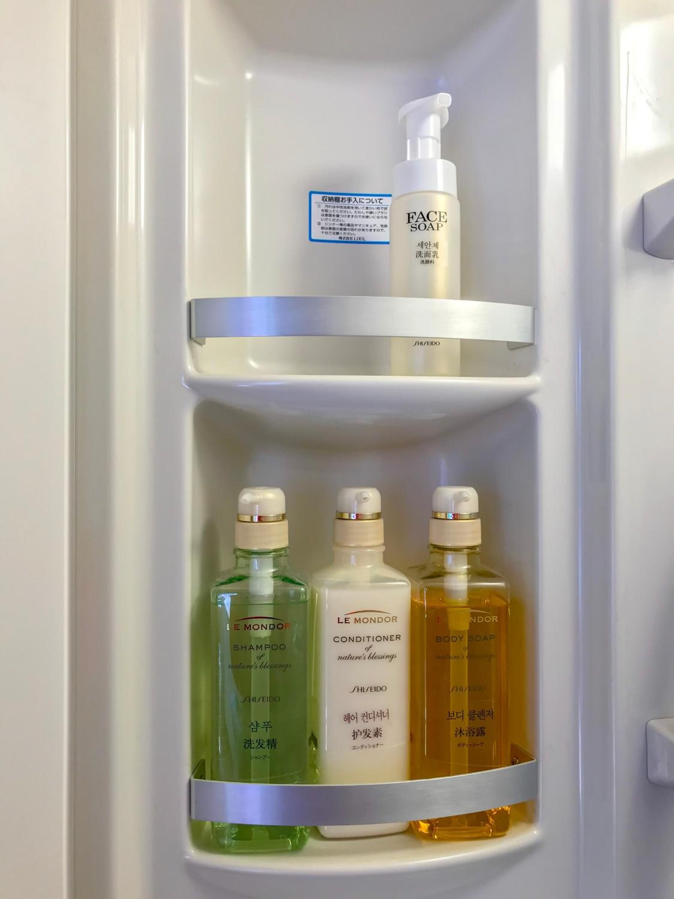 A bathroom shelf with three bottles of Le Mondor products: shampoo, conditioner, and body soap.
