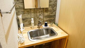 Una cocina compacta con encimera de madera, un lavamanos de acero inoxidable, un grifo, una cafetera y una pequeña planta en maceta.