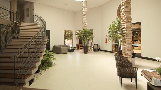 A spacious lobby with a staircase, seating area, and a tall stack of books as a decorative feature. - Terras Hotel (Lucas do Rio Verde)