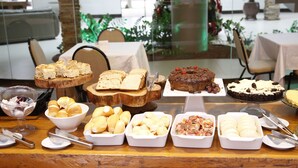 A buffet table with various food items including bread, pastries, and desserts. - Terras Hotel (Lucas do Rio Verde)