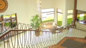A spacious indoor area with a staircase, a stone pillar, and a seating area with a view of the outdoors. - Terras Hotel (Lucas do Rio Verde)