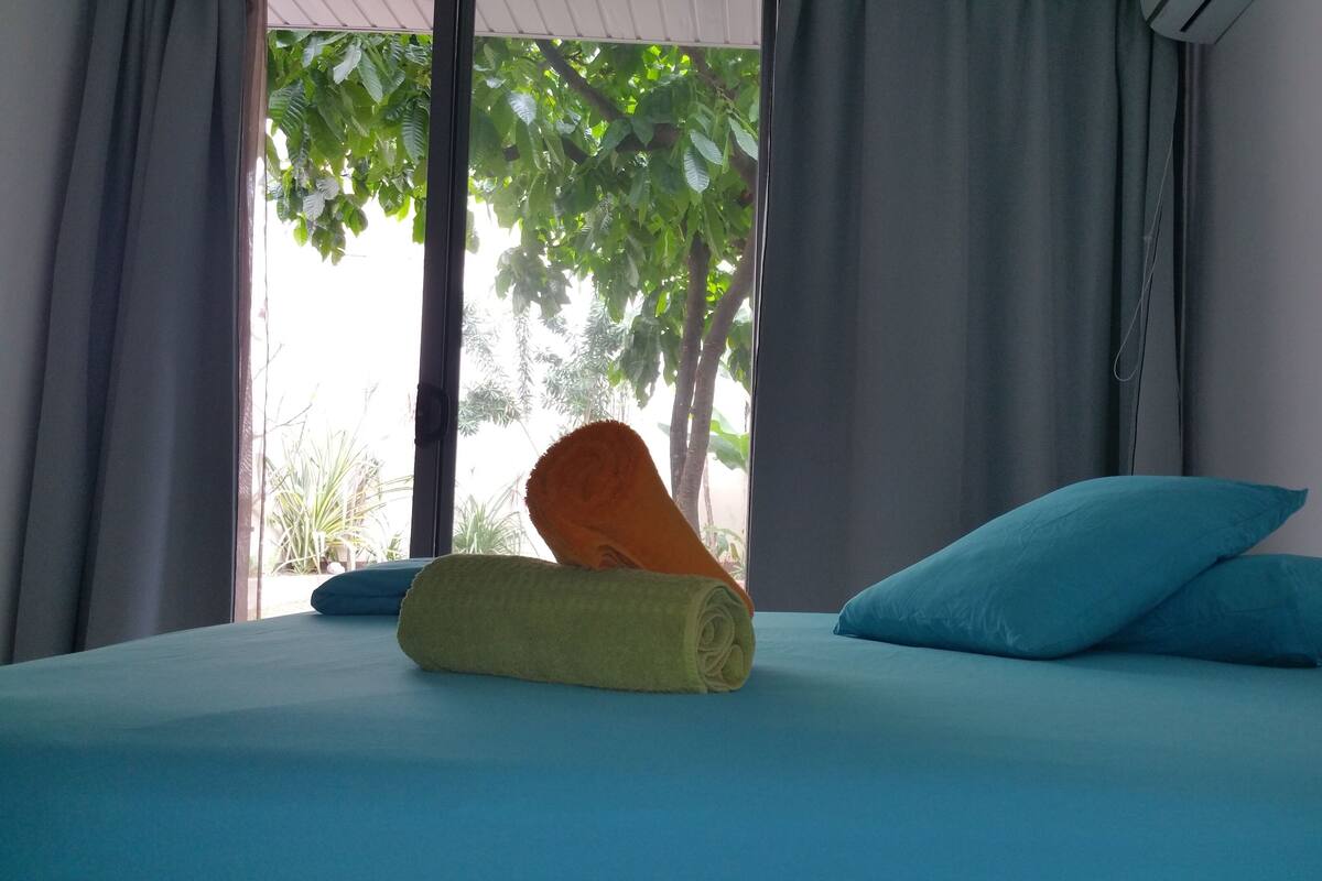 Een bed met een blauwe matras, een gele handdoek en een blauw kussen.