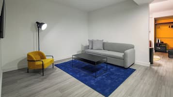 A modern living room with a sofa, a coffee table, a lamp, and a chair.