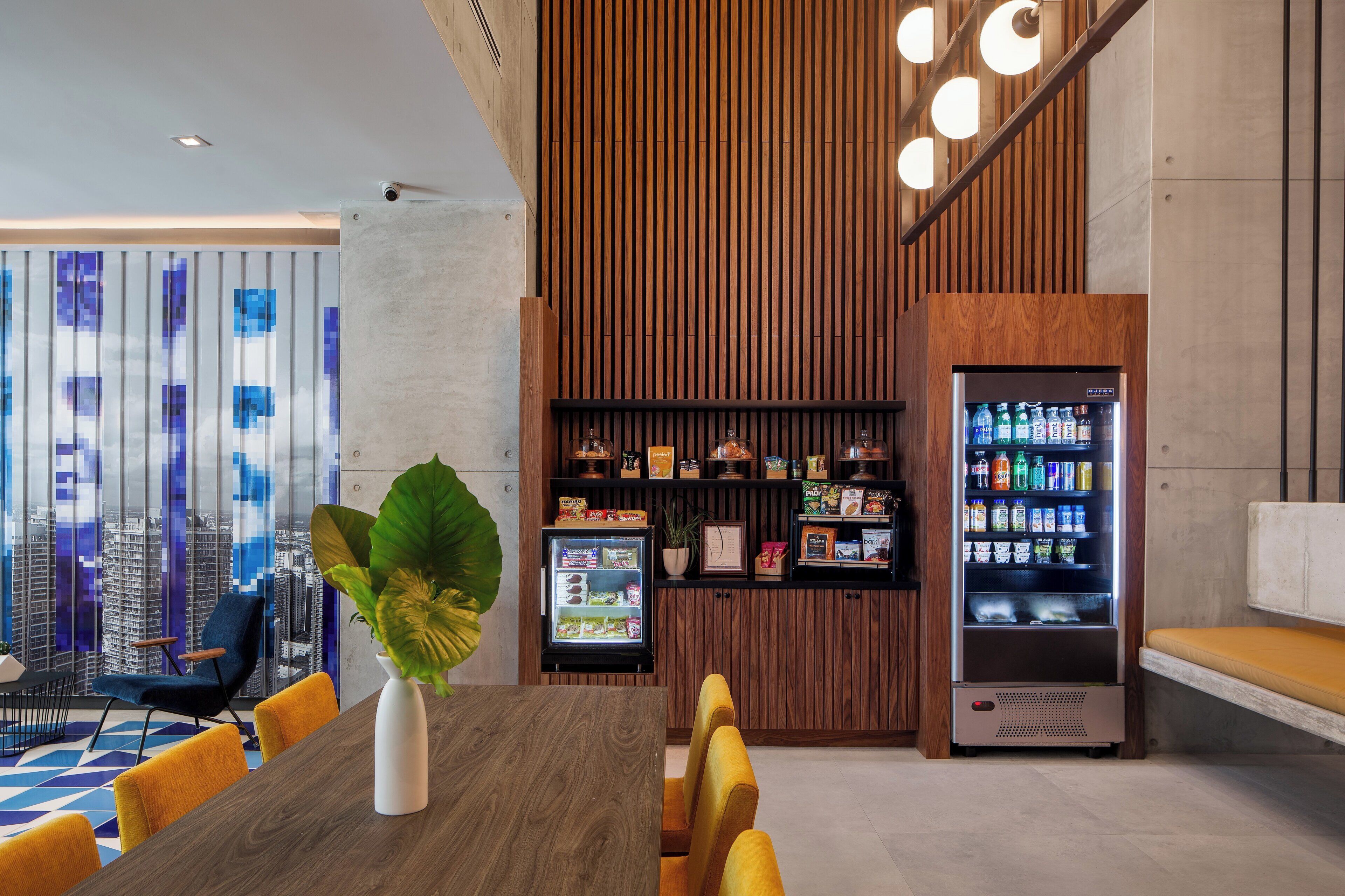 A modern interior with a dining area, a vending machine, and a view of the cityscape.