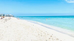 A beach with clear blue water, white sand, and a few people swimming. - Hotel Indigo Miami Brickell by IHG (Miami)