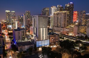 A cityscape at night with high-rise buildings, a prominent hotel with a large illuminated sign, and a busy street with traffic. - Hotel Indigo Miami Brickell by IHG (Miami)