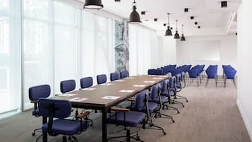 A conference room with a long table, blue chairs, and pendant lighting.