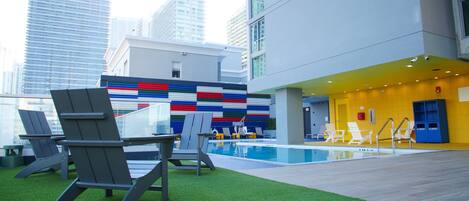 An outdoor pool area with lounge chairs and a modern building in the background.