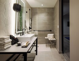 A modern bathroom with a vanity, a shower, and a towel rack.