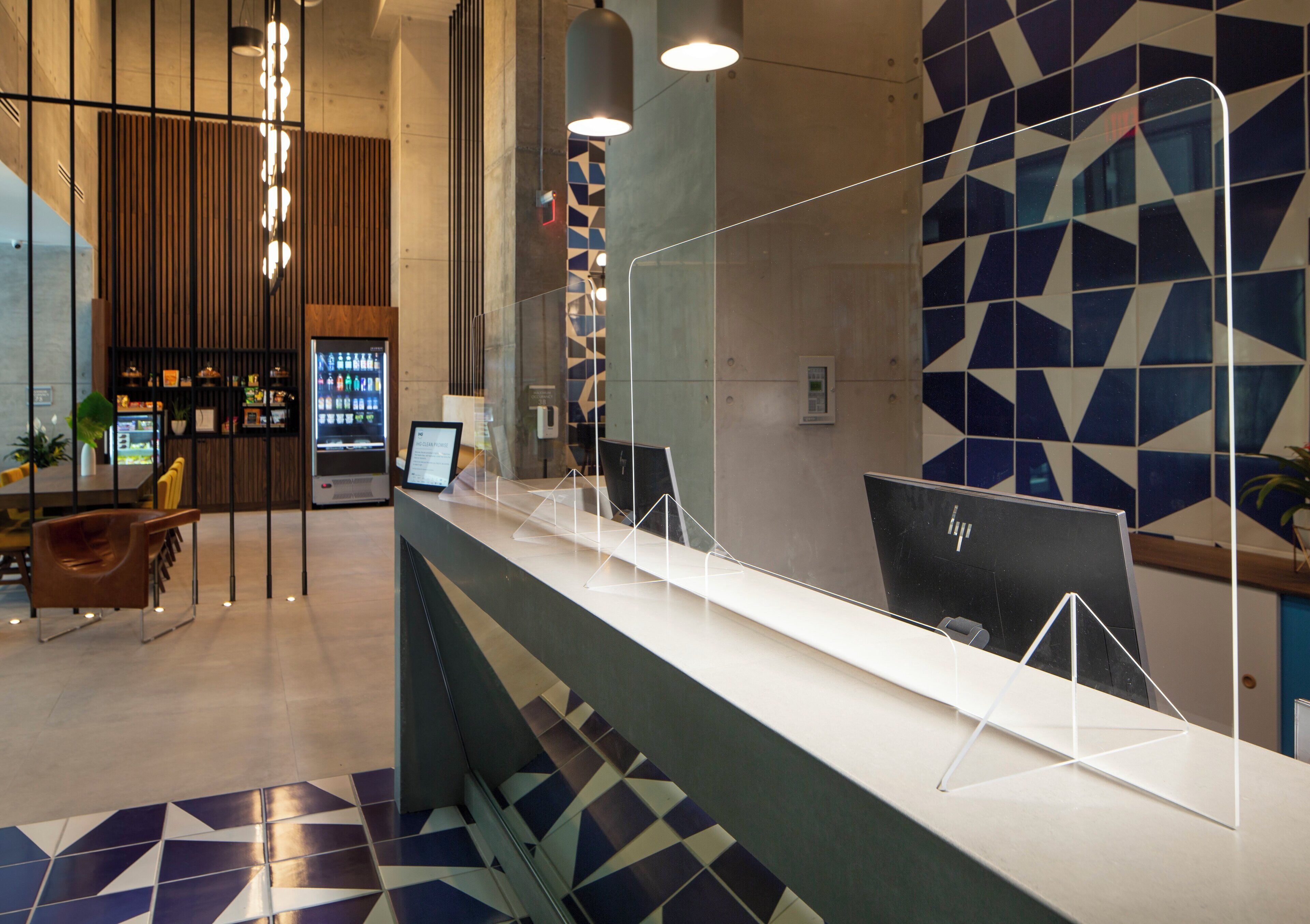 Una recepció de disseny modern, una zona de seients amb cadires, una màquina expenedora i una paret amb un disseny decoratiu.