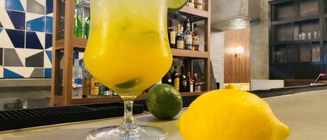 Un bar con una copa de cóctel, una rodaja de lima y un limón entero sobre la barra.