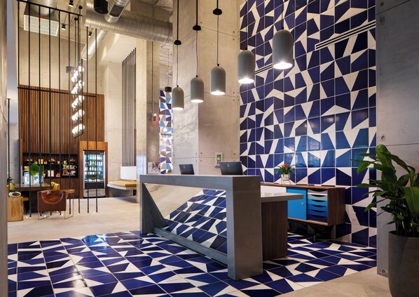 A modern reception area with a geometric tile floor, a reception desk, and a seating area with a wooden partition. - Hotel Indigo Miami Brickell by IHG (Miami)