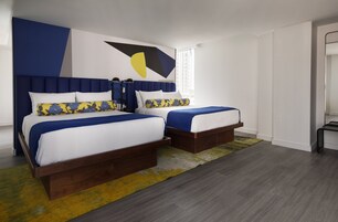 A modern bedroom with two beds, a geometric wall art piece, and a large window.