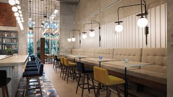 A modern restaurant interior with a bar area, seating, and pendant lighting.