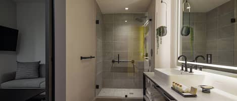 A modern bathroom with a glass-enclosed shower, a large mirror, and a vanity with towels.