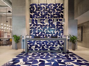A reception area with a geometric patterned wall, a reception desk, and potted plants. - Hotel Indigo Miami Brickell by IHG (Miami)
