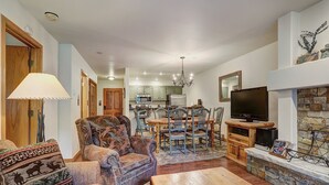 A spacious living room with a fireplace, a television, and a dining area with chairs and a table. - Newly Renovated 2 Bed/ 2 Bath Beaver Creek  2 Bedroom Condo by RedAwning (Avon)