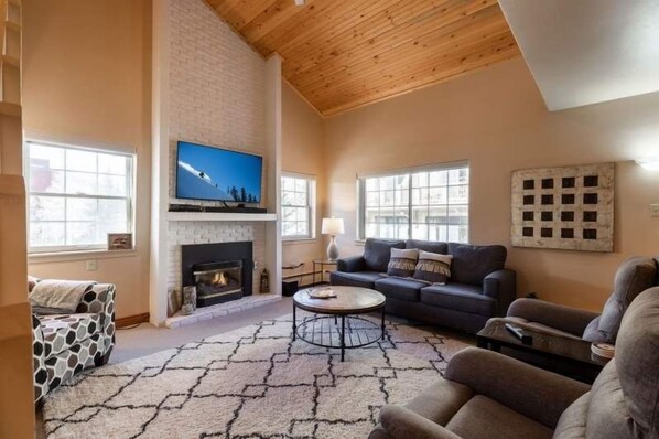 Cozy living room with a large flat-screen TV, fireplace, and comfortable sofa set.