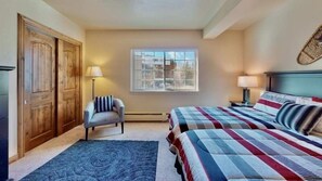 Enjoy a restful stay in this serene bedroom with a double bed, comfortable chair, and large window offering a view of the outside.