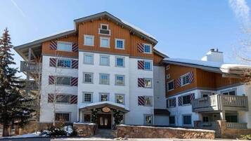 A multi-story hotel with a central entrance, balconies, and a stone facade.