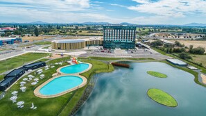 A modern hotel with a central courtyard featuring two swimming pools, a children's play area, and a large building with a glass facade. - MDS Hotel Chillan (Chillan)