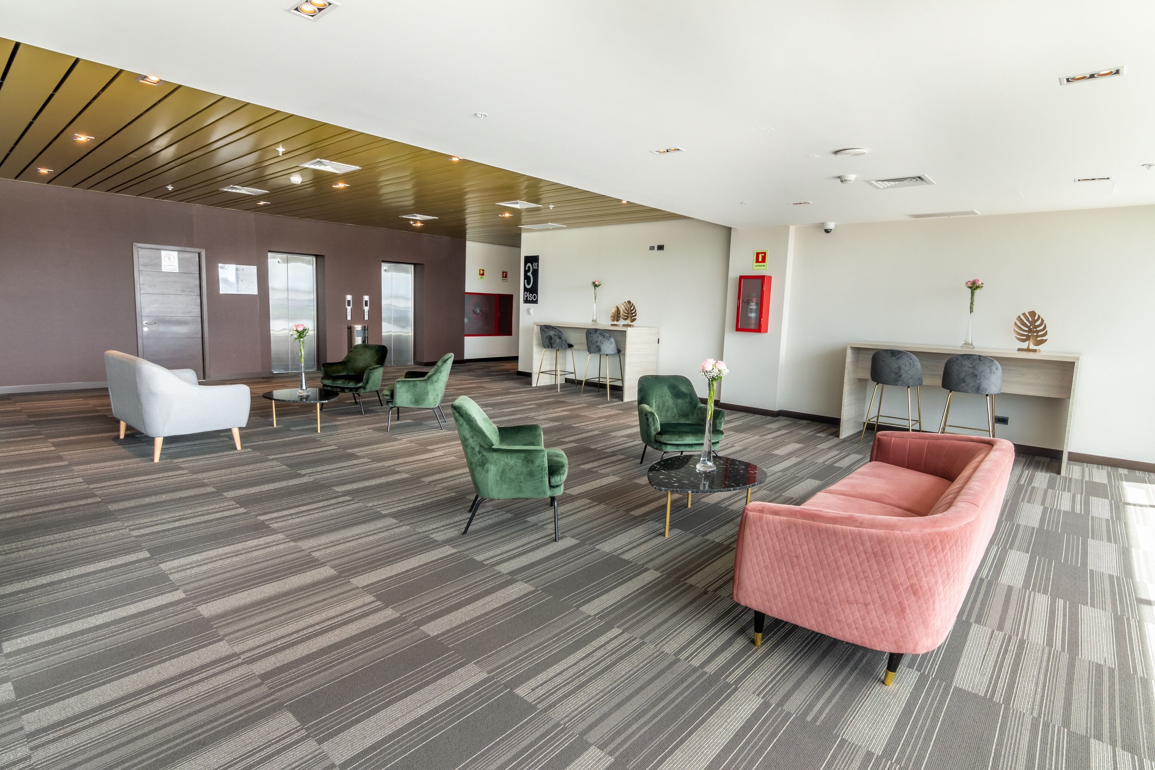 A spacious lobby with modern furniture, a reception desk, and a wall-mounted information board.