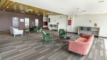 A spacious lobby with modern furniture, a reception desk, and a wall-mounted information board.