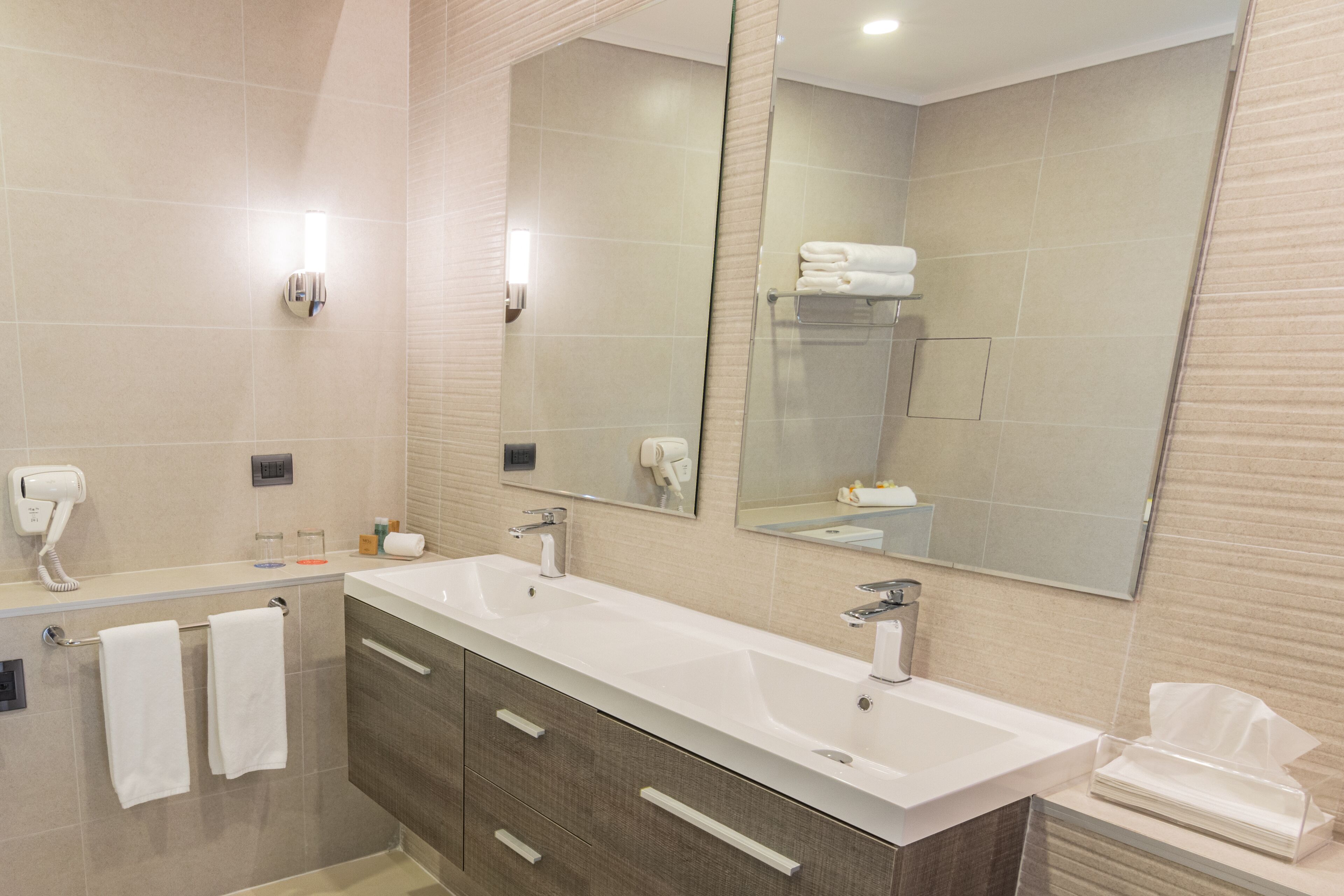 A modern bathroom with a large mirror, two sinks, and a towel rack.
