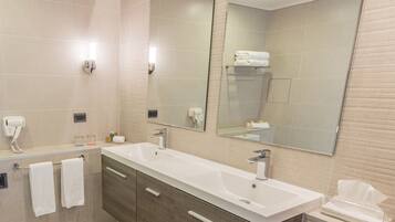 A modern bathroom with a large mirror, two sinks, and a towel rack.
