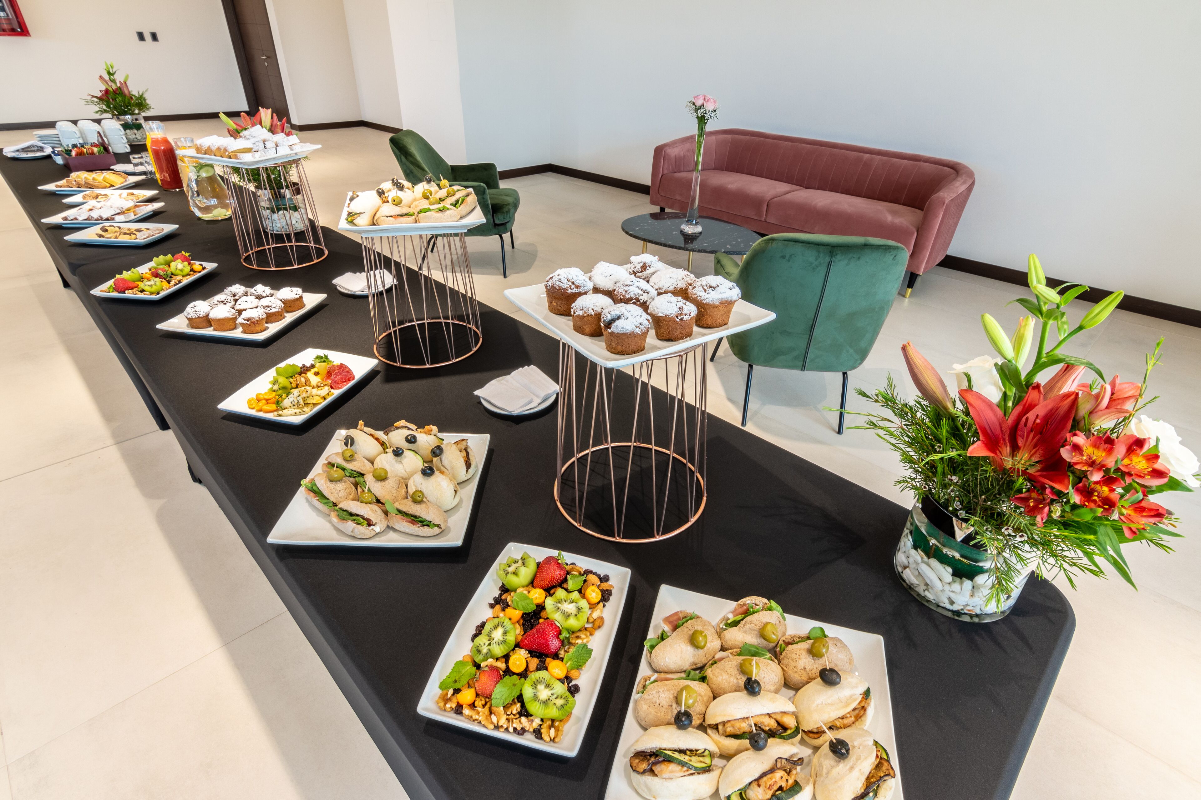 A buffet table with various food items and a red couch in the background.