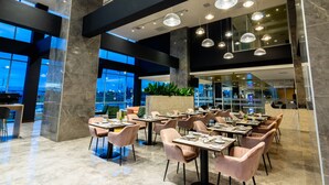 Un restaurant moderne doté de sols en marbre, de grandes fenêtres et d’un éclairage contemporain.