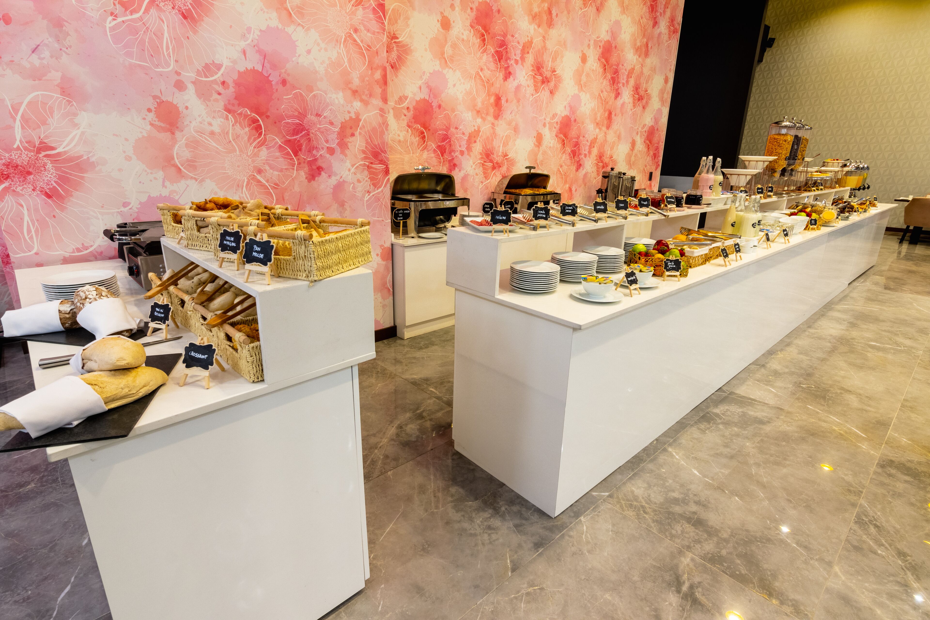 Un buffet proposant une variété de plats et de boissons, notamment du pain, des pâtisseries et un coin café.
