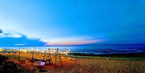 Una playa con un columpio y una fila de luces a lo largo de la orilla.