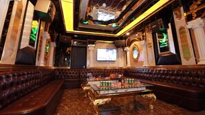 Un área de estar lujosa con asientos mullidos, una mesa de centro de mármol y una máquina de karaoke.