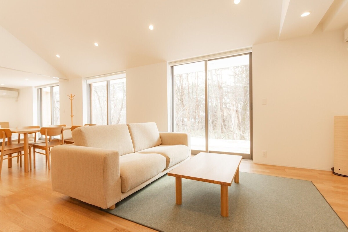 A spacious living room with a sofa, a coffee table, and a dining area with chairs and a table.