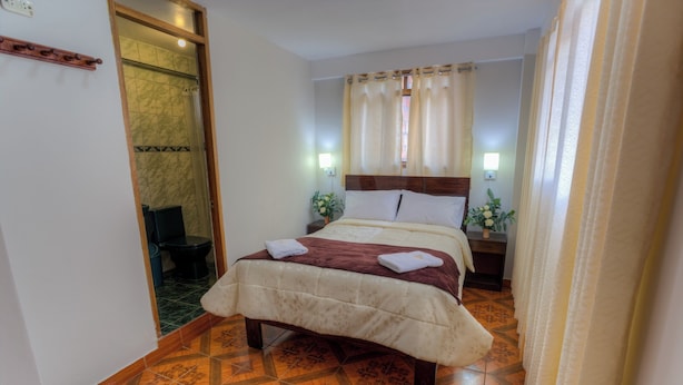Une chambre d’hôtel comprenant un lit, une table de chevet, une lampe et un espace douche.