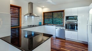 Eine moderne Küche mit einer zentralen Kochinsel, weißen Schränken, einem eingebauten Backofen und einer Mikrowelle.