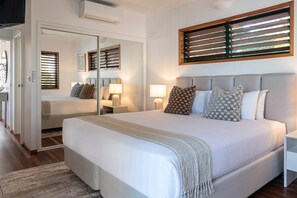 Une chambre moderne avec un grand lit, des lampes de chevet, un miroir et une fenêtre avec des stores.