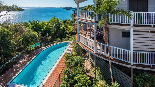 Ein zweistöckiges Gebäude mit Pool und Meerblick.